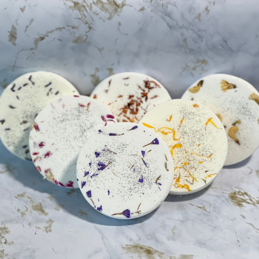 A collection of round shower steamers with embedded dried flowers. 