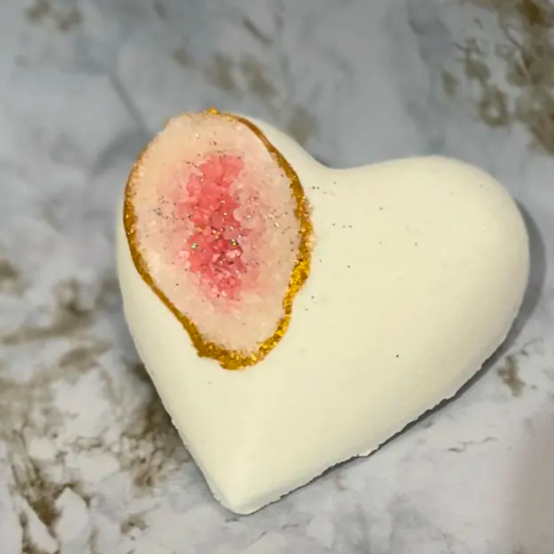 Heart-shaped bath bomb with a pink center on a marble surface