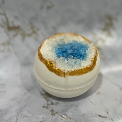 Geode bath bomb with a blue center on a marble surface