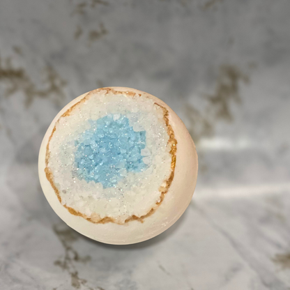 Bath bomb with a light blue center on a marble surface