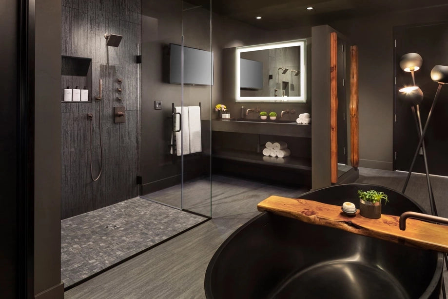 Modern bathroom with dark walls, a shower, and a bathtub with a bath bomb on a wooden tray.