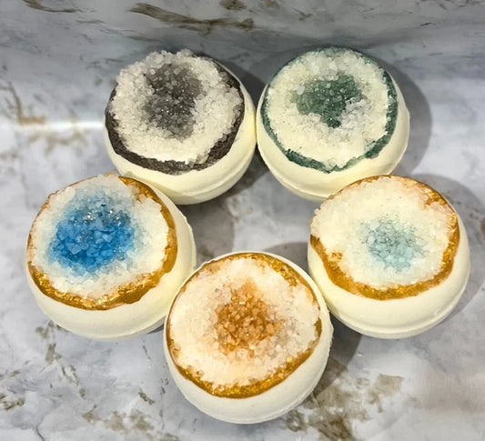 Five bath bombs with colorful interior patterns on a marble surface