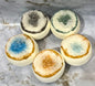 Five bath bombs with colorful interior patterns on a marble surface