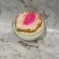 Bath bomb with pink center and gold top on a marble surface