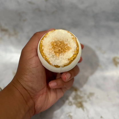 Hand holding a gold geode bath bomb with a marble background