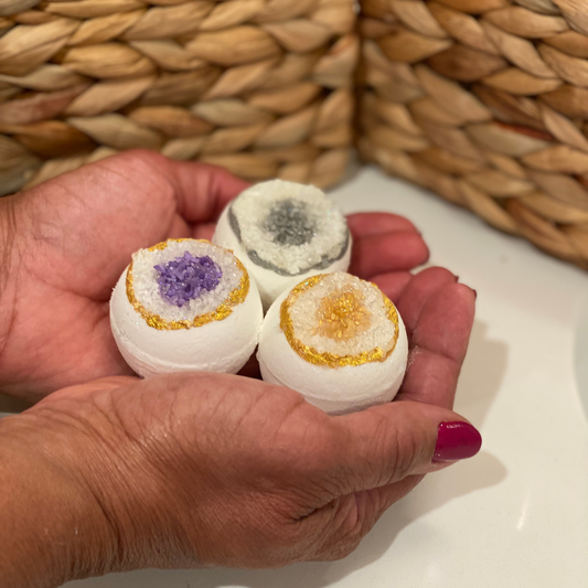 Three mini geode bath bombs with varying colors and patterns, held in a person's hand.