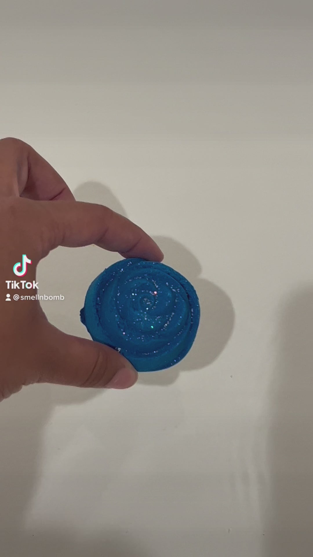 A video showing a blue rose-shaped bath bomb with glitter fizzing in the water.